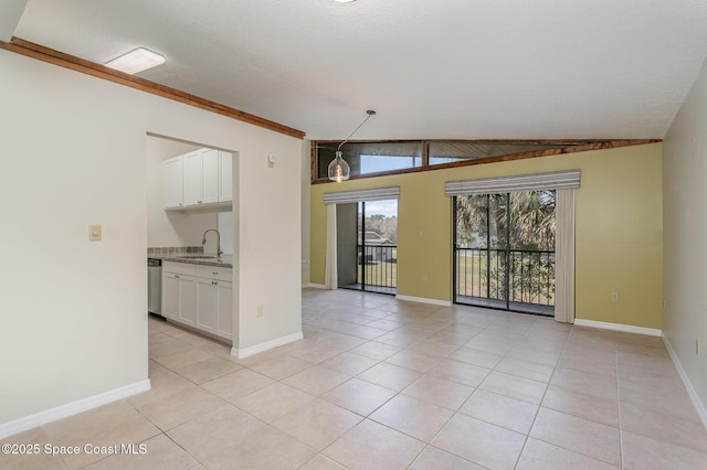 empty room with lofted ceiling, sink, a textured ceiling, and light tile patterned floors