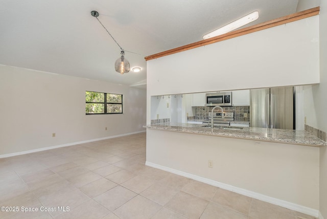 kitchen with stainless steel appliances, light stone counters, white cabinets, decorative light fixtures, and vaulted ceiling