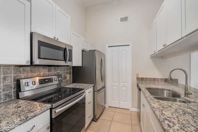 kitchen with sink, light stone countertops, white cabinets, and appliances with stainless steel finishes