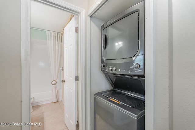 laundry area featuring light tile patterned floors and stacked washer / dryer