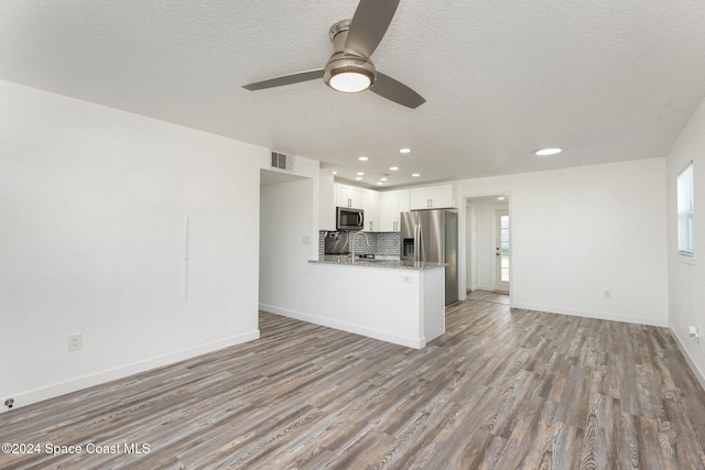 unfurnished living room featuring light wood-type flooring, ceiling fan, and a textured ceiling