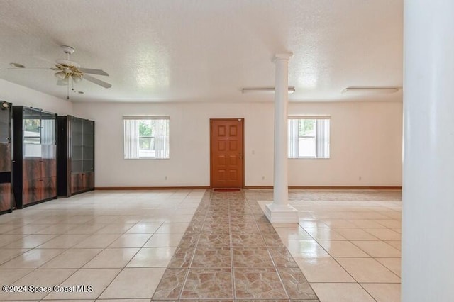 tiled spare room featuring a wealth of natural light, ornate columns, a textured ceiling, and ceiling fan