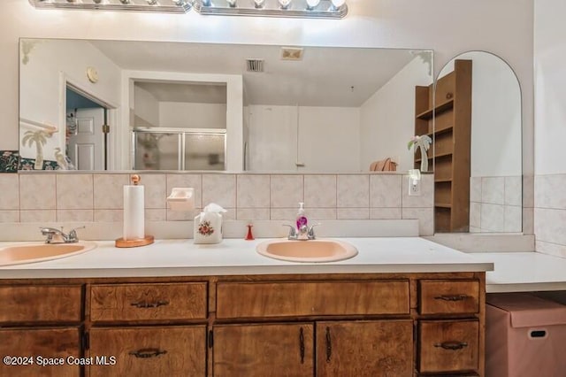 bathroom featuring vanity, decorative backsplash, and a shower with shower door