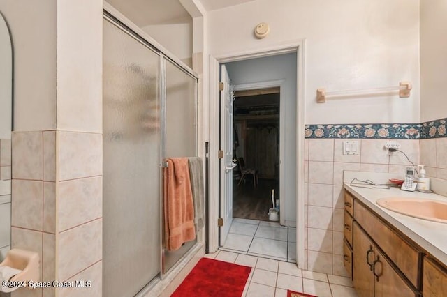 bathroom featuring tile walls, vanity, a shower with shower door, and tile patterned floors