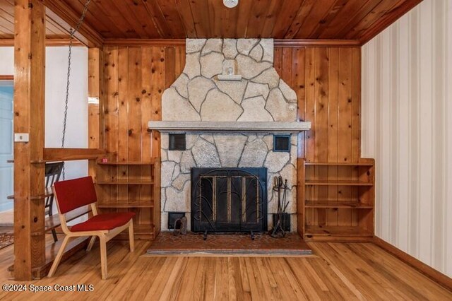 unfurnished living room featuring wood ceiling, hardwood / wood-style floors, ornamental molding, a fireplace, and wooden walls