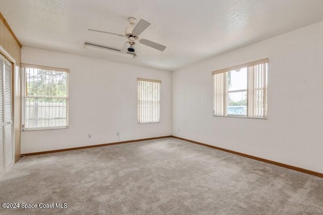 empty room featuring ceiling fan, a textured ceiling, and light colored carpet