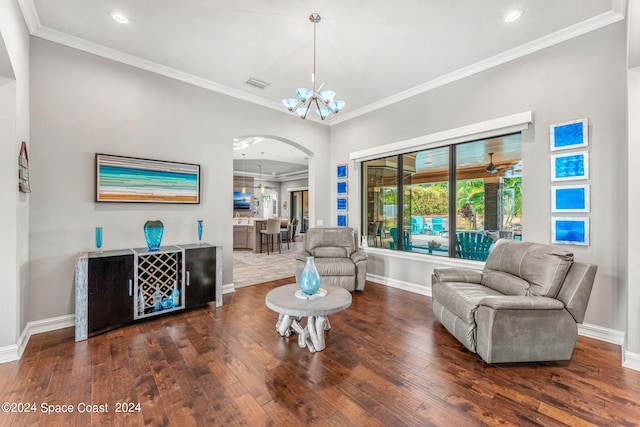 living room with ceiling fan with notable chandelier, dark hardwood / wood-style flooring, and crown molding