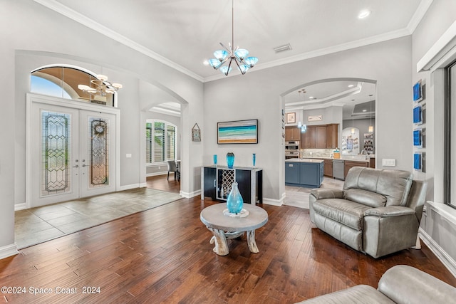 living room with dark hardwood / wood-style flooring, french doors, ornamental molding, and an inviting chandelier