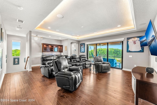 living room featuring hardwood / wood-style flooring, a textured ceiling, and a tray ceiling