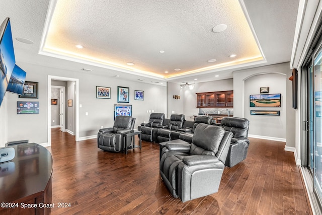 living room with a tray ceiling, a textured ceiling, and dark hardwood / wood-style floors