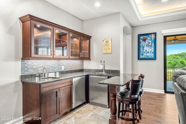 bar featuring crown molding, decorative backsplash, sink, and dark stone counters