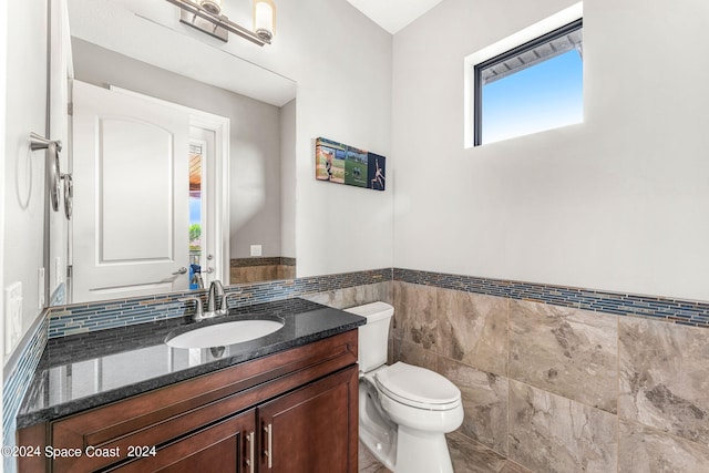 bathroom with vanity, toilet, and tile walls