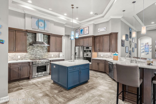 kitchen featuring wall chimney exhaust hood, a towering ceiling, decorative light fixtures, decorative backsplash, and appliances with stainless steel finishes