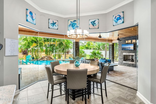 tiled dining space with an inviting chandelier, a stone fireplace, and crown molding