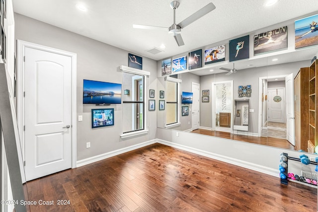 workout room with ceiling fan, wood-type flooring, and a textured ceiling