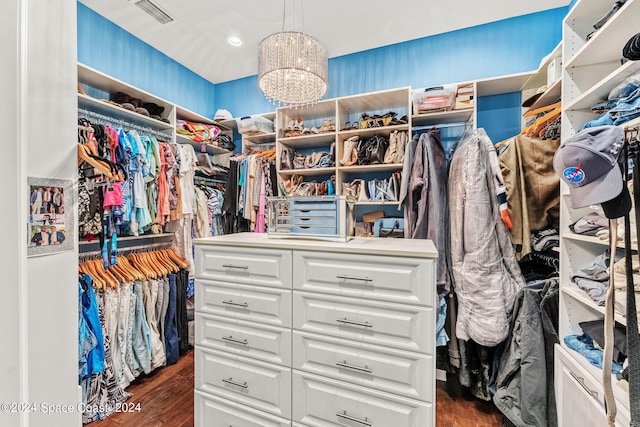 walk in closet featuring dark wood-type flooring and an inviting chandelier