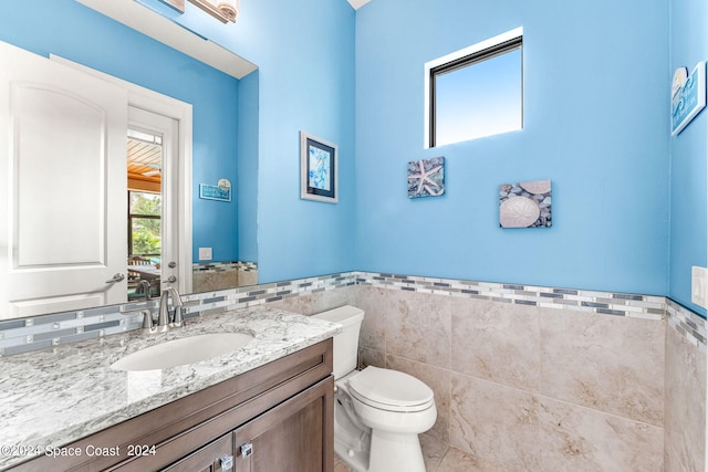 bathroom with vanity, toilet, and tile walls