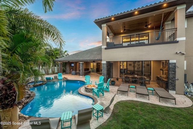 pool at dusk with ceiling fan, an outdoor fire pit, and a patio