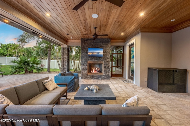 patio terrace at dusk featuring an outdoor living space with a fireplace and ceiling fan