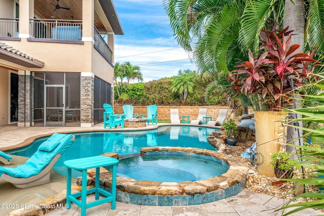 view of pool with an in ground hot tub, ceiling fan, a patio area, and a sunroom