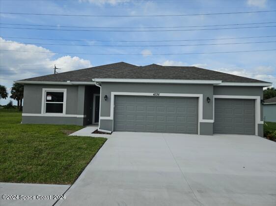 view of front facade featuring an attached garage, a front lawn, stucco siding, and driveway