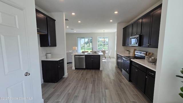 4346 Kelsey Ln, Sebastian, FL 32976 - kitchen with stainless steel appliances, light wood-style floors, recessed lighting, light countertops, and a center island