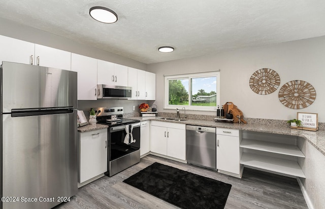 kitchen with white cabinets, light hardwood / wood-style floors, appliances with stainless steel finishes, and sink