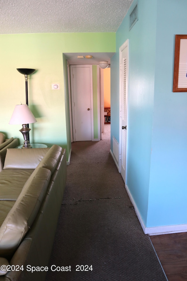 corridor with a textured ceiling and hardwood / wood-style flooring