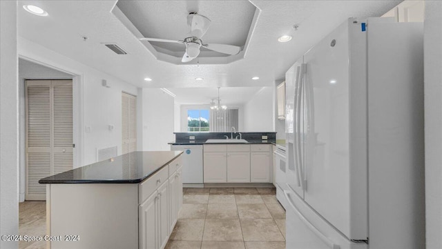 kitchen with sink, kitchen peninsula, white appliances, white cabinetry, and ceiling fan with notable chandelier