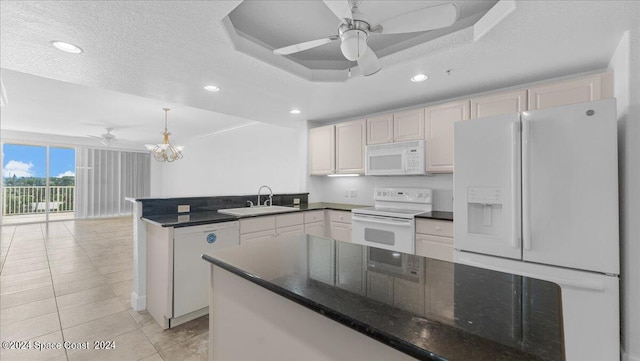 kitchen with ceiling fan with notable chandelier, white appliances, sink, and kitchen peninsula