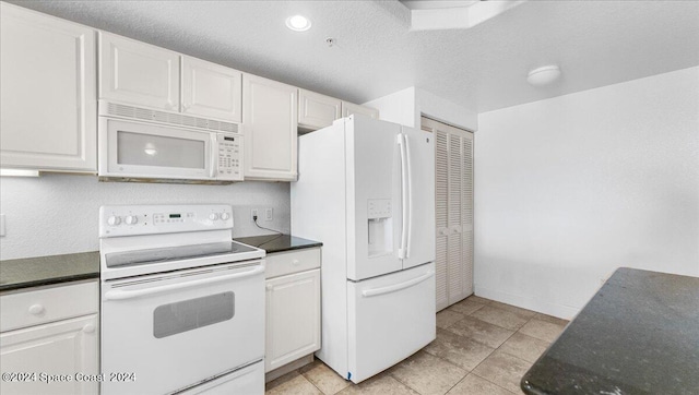 kitchen featuring a textured ceiling, white appliances, light tile patterned floors, and white cabinets