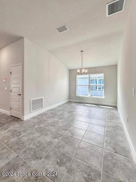 1182 Tupelo Cir, Cocoa, FL 32926 - unfurnished dining area featuring baseboards, a chandelier, a textured ceiling, and lofted ceiling