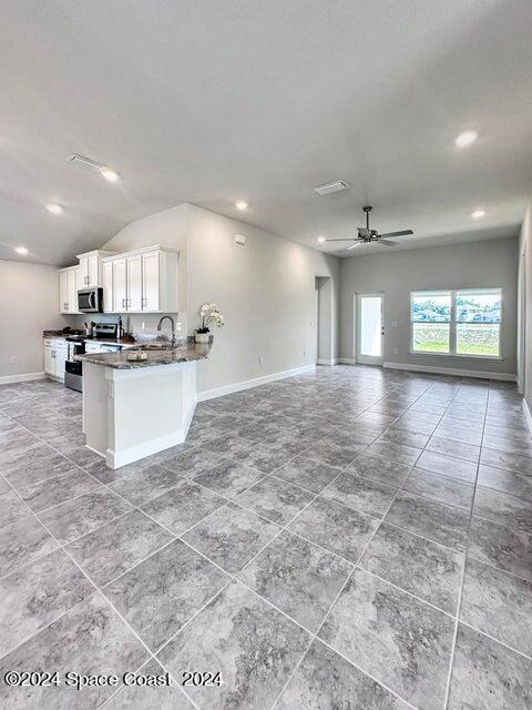 kitchen featuring ceiling fan, kitchen peninsula, white cabinetry, appliances with stainless steel finishes, and dark stone countertops