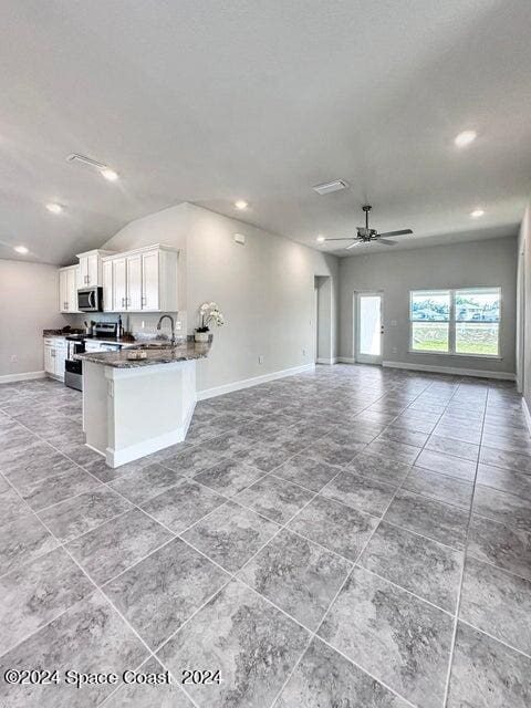 1182 Tupelo Cir, Cocoa, FL 32926 - kitchen with stove, open floor plan, baseboards, white cabinetry, and lofted ceiling