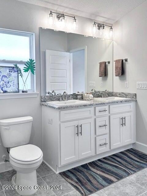 bathroom featuring vanity, tile patterned flooring, toilet, and a textured ceiling