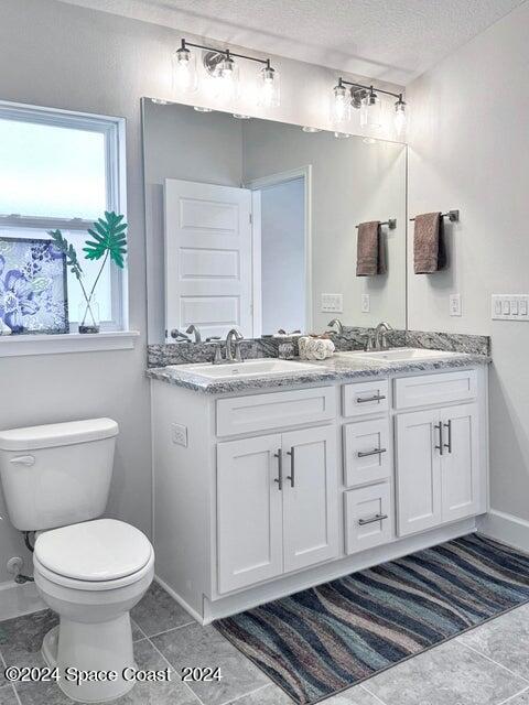 1182 Tupelo Cir, Cocoa, FL 32926 - full bath featuring a textured ceiling, double vanity, toilet, and baseboards