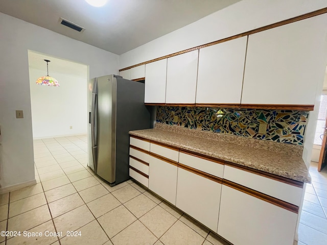 kitchen with hanging light fixtures, decorative backsplash, light tile patterned flooring, white cabinetry, and stainless steel fridge