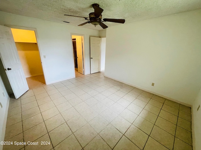 unfurnished bedroom featuring ceiling fan, a textured ceiling, a closet, and a spacious closet