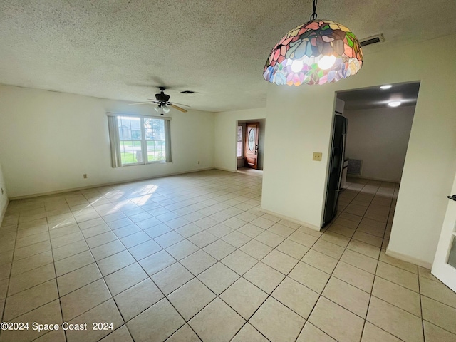 tiled empty room with ceiling fan and a textured ceiling