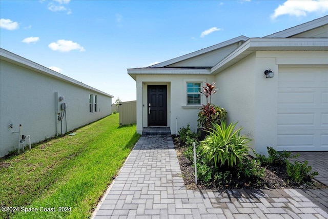 1447 Colebrook Cir SW, Palm Bay, FL 32908 - view of exterior entry with a lawn, stucco siding, and an attached garage