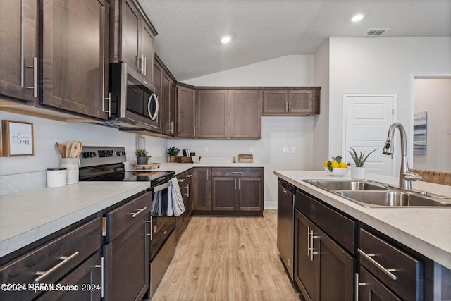 kitchen featuring sink, stainless steel appliances, dark brown cabinetry, vaulted ceiling, and light hardwood / wood-style flooring