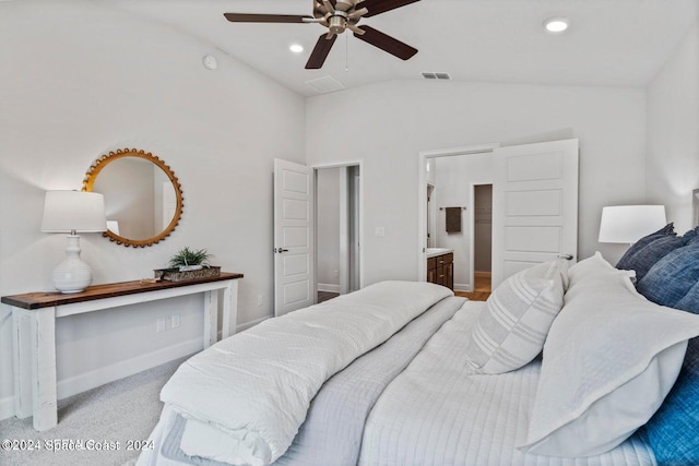 carpeted bedroom featuring ceiling fan, vaulted ceiling, and ensuite bath