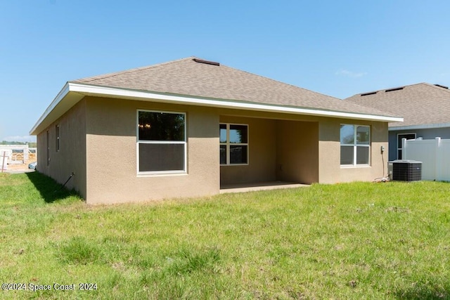 back of property with a yard and central air condition unit