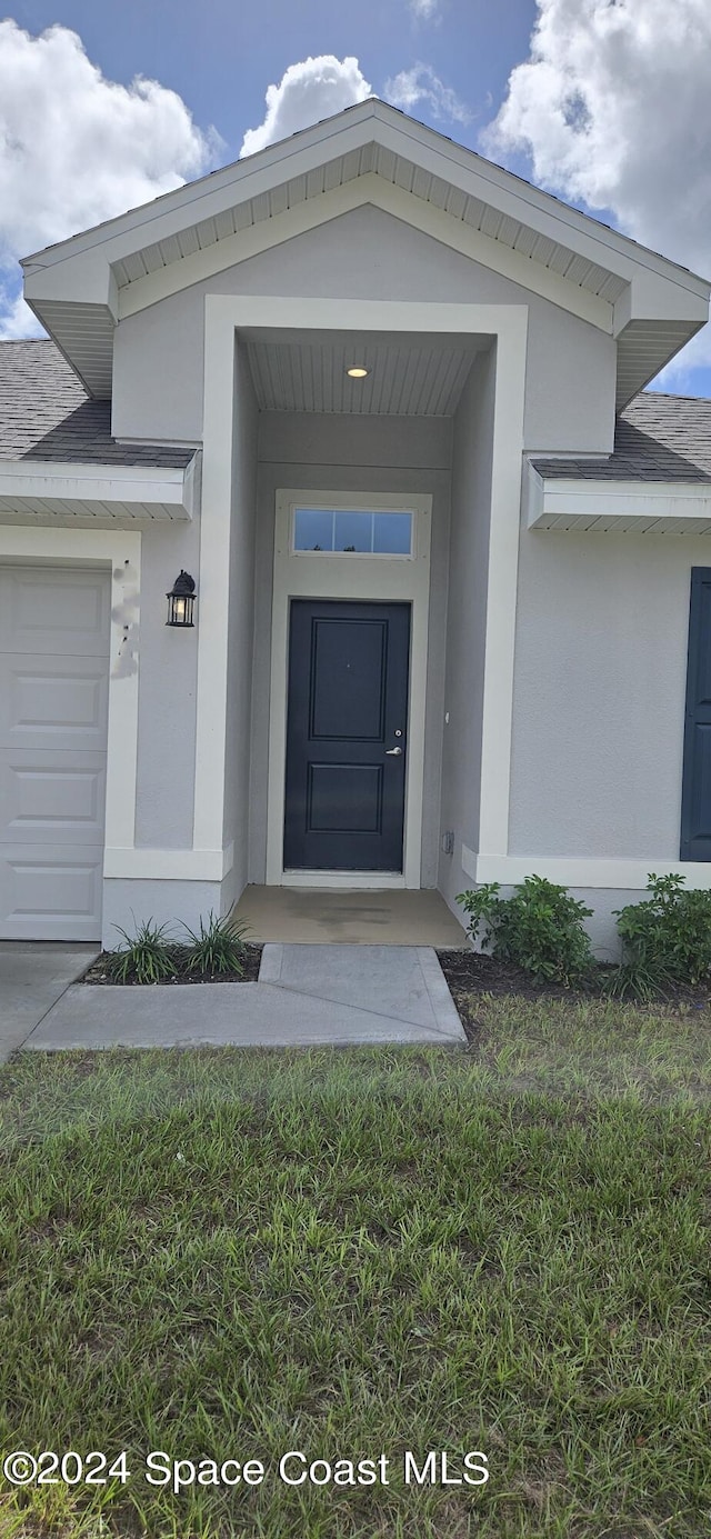 doorway to property featuring a yard and a garage