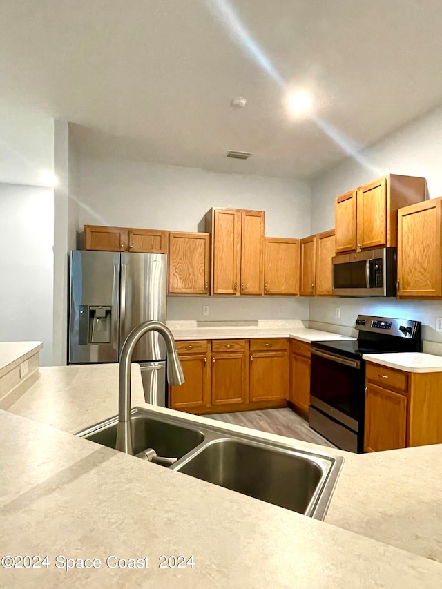 kitchen with stainless steel appliances, sink, and light wood-type flooring