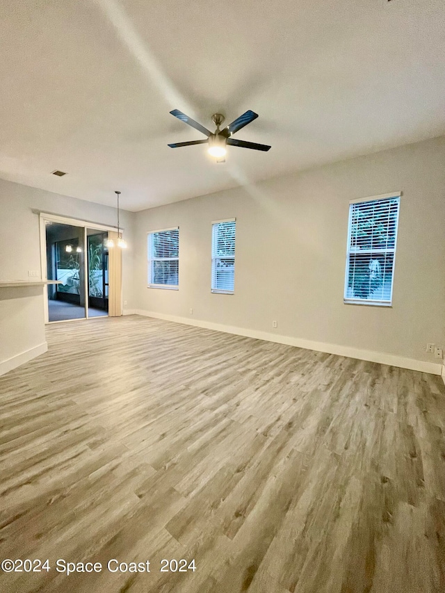 unfurnished living room with light hardwood / wood-style flooring, a healthy amount of sunlight, and ceiling fan