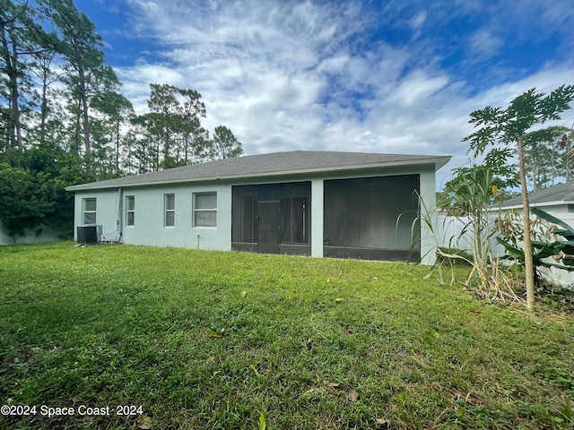 back of property with central AC, a sunroom, and a lawn