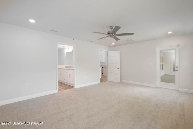 unfurnished bedroom with ceiling fan, ensuite bath, and light carpet