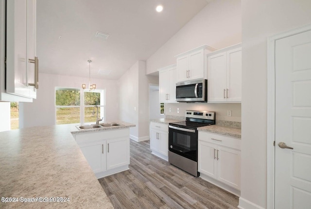 kitchen with white cabinets, lofted ceiling, sink, stainless steel appliances, and light hardwood / wood-style floors