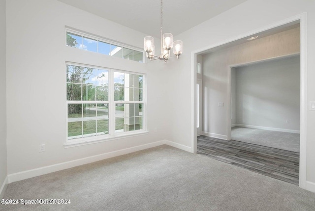 unfurnished dining area featuring a chandelier, carpet flooring, and baseboards